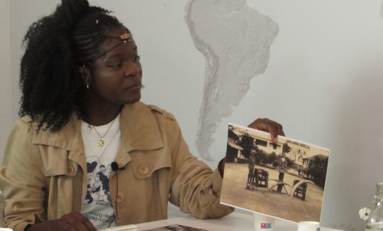 Rusly Cachina Esapa mostra una postal de la col·lecció de Núñez de
Prado, del 1929, amb una imatge presa al Palacio de Gobierno on es mostren unes cadires i una sèrie de peces de l’exgovernador de Guinea Equatorial. Imatge presa durant la Taula de Diàleg amb membres de la comunitat guineana a Barcelona celebrada el 16 de març de 2023
